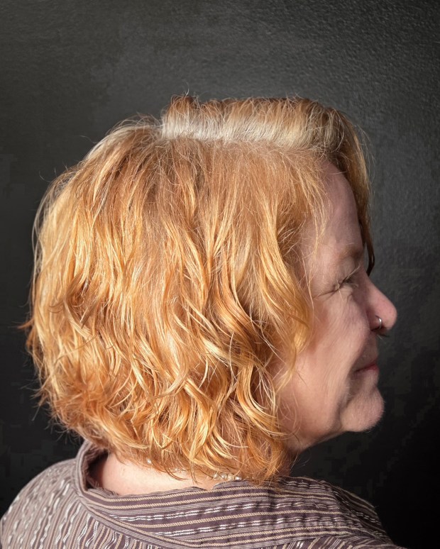 Side profile of a golden blonde bob with tight, tousled waves and layered texture.