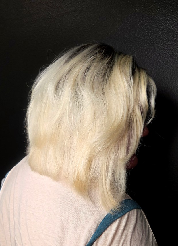 Side-back view of a bright blonde long bob with soft layers and textured, flipped-out ends.