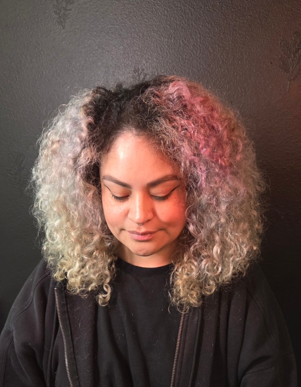 Front view of a woman with voluminous, tight curls and a rounded haircut, showing off natural texture and definition.
