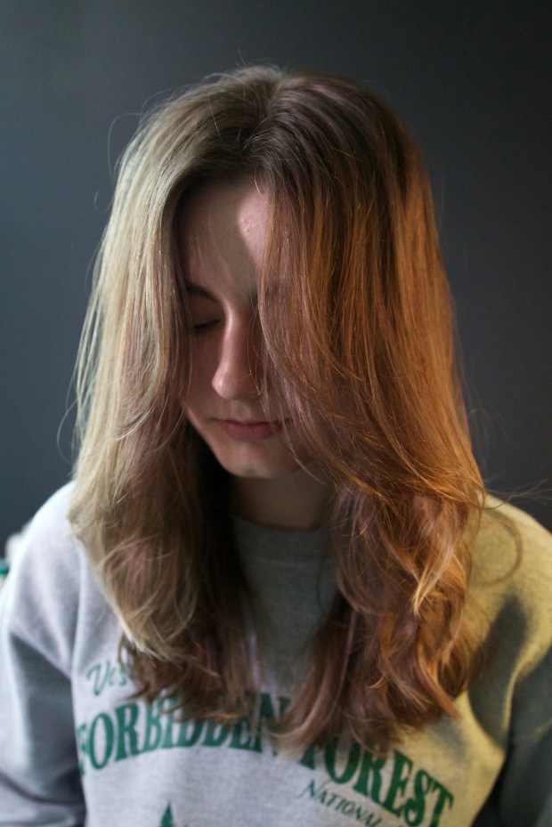 Front view of a long haircut with soft, face-framing layers and natural waves on light brown hair.