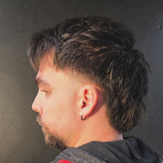 Side profile of a men’s modern mullet with a clean skin fade on the sides and textured length through the back.